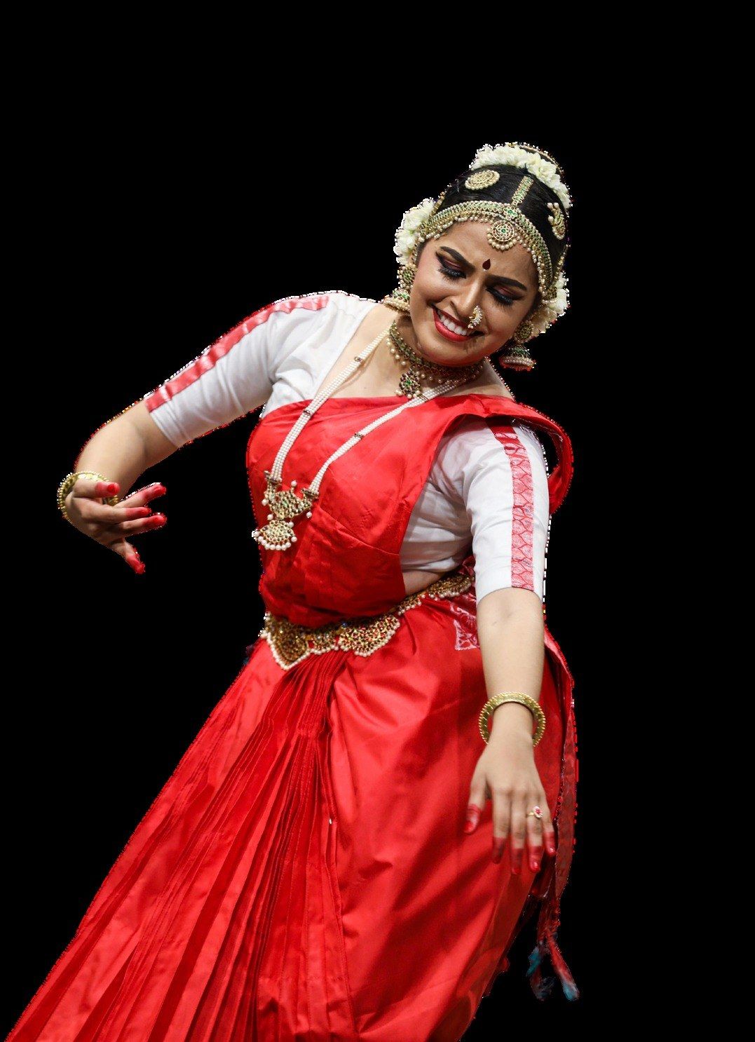 Medha Mayuri in a red costume against a black ground, arms held in a completed pose.